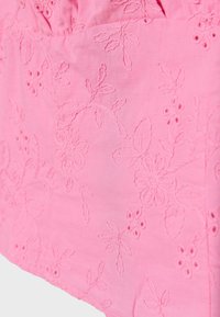 Tissu rose avec motifs floraux et feuillages brodés avec un fil assorti, comprenant des petits détails découpés et une couture texturée.