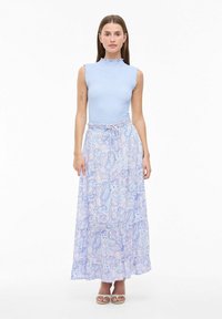 Top senza maniche a righe blu chiaro con scollatura arricciata, abbinato a una lunga gonna fluida con stampa paisley in morbidi toni di blu e lilla.