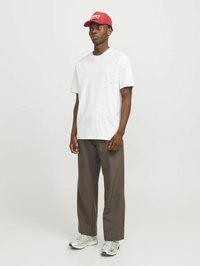 Hvid T-shirt med korte ærmer, løstsiddende brune bukser, grå sneakers med en tekstureret sål, og en rød baseballkasket med logo detalje.