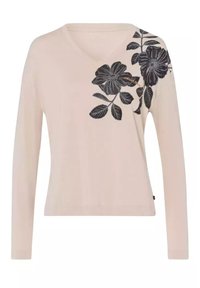 Króki rękaw z dekoltem w serek w jasnym beżu z ciemnym kwiatowym wzorem, w którym po lewej stronie znajdują się liście i kwiaty, wykonany z miękkiego materiału.