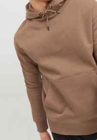 Sudadera marrón hecha de tela suave, con un bolsillo tipo canguro, capucha con cordón y puños acanalados. Textura lisa con detalles de diseño mínimos.