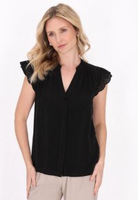 Blusa nera con maniche corte a volant, dettagli in pizzo, frontale con bottoni e vestibilità rilassata. Tessuto liscio e leggero.
