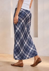 Navy plaid maxi skirt in lightweight fabric, featuring white and light blue patterns. Paired with brown flat shoes.