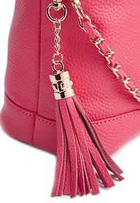 Różowa skórzana torebka z teksturowaną powierzchnią, złotymi łańcuszkami i dekoracyjną skórzaną frędzlą w różnych odcieniach różu.