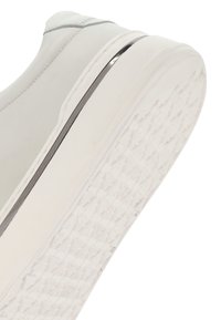 Sneaker bianco in pelle con finitura liscia, caratterizzato da un profilo basso e una suola in gomma testurizzata. Accento metallico nella zona della suola intermedia.