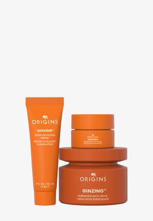 Trois produits de soin Origin GinZing orange : sérum illuminateur, crème contour des yeux éclaircissante et crème riche énergisante.