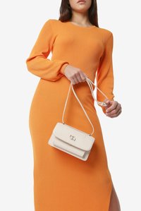 Hvid læderhåndtaske med magnetlukning, glat tekstur og guldhardware, parret med en ribbet orange langærmet kjole.