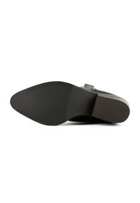 Black leather shoe sole with a textured surface, featuring a rounded shape and smooth edges. Stamped branding near the heel.