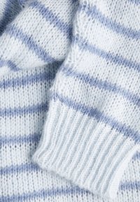 Világos kék pulóver puha, bolyhos textúrával. Az anyag világoskék és sötétebb kék váltakozó csíkokkal készült. Bordás mandzsetták és alján is bordás szegély.