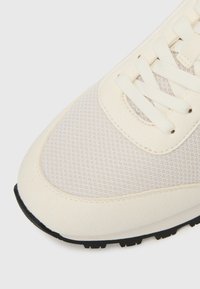 Kremkrāsas sneakeri ar sietu un gludas ādas augšdaļu, apaļu purngalu un plakaniem šņorēm. Gumijas zole ar reljefu gripu.