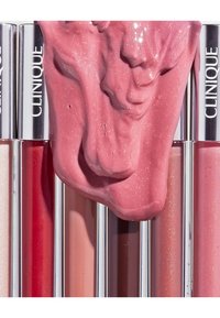 Clinique Lippenprodukte in zylindrischen Behältern, die Nuancen von Rosa und Rot aufweisen. Glänzende Textur mit einer rosa Creme, die obenauf getropft ist.