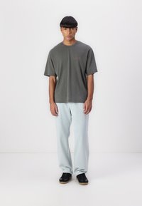 Gray oversized T-shirt with a crew neckline, paired with light blue straight-leg jeans and black sneakers with gum soles.