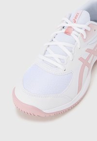 Weißer Sportschuh mit pinken Akzenten, ausgestattet mit einem Obermaterial aus Mesh, strukturierten Oberflächen und einer runden Zehenpartie. Leichtes Design und Gummisohle.