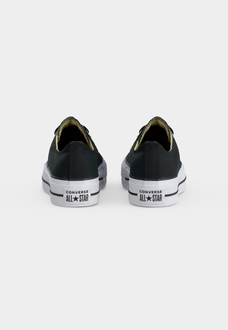 Coppia di sneakers nere Converse All Star basse viste da dietro, con suole di gomma bianche e logo del marchio sul tallone.