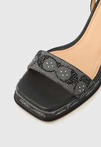 Μαύρο και ασημένιο πεδιλάκι με τακούνι και τετράγωνη μύτη, με ραβδωτό λουράκι διακοσμημένο με μικρές χάντρες και λείο μαύρο πέλμα.