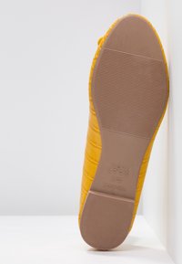 Yellow faux leather flat shoe with a textured croc pattern, rubber sole, and a rounded toe. Brand label visible on the sole.