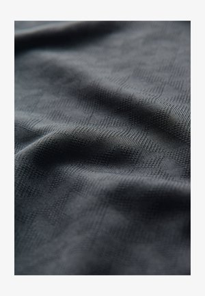 Tela negra texturizada con un sutil patrón geométrico, que muestra una apariencia suave y tejida, con reflejos de luz variables en la superficie.