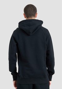 Felpa nera con cappuccio, dotata di polsini e orlo a coste. Realizzata in morbido tessuto con una superficie liscia. Presenta un design semplice senza decorazioni.