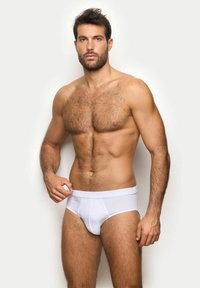 Slip di cotone bianco con una texture liscia e cintura elastica, indossati da un modello maschile con capelli scuri e fisico tonico.