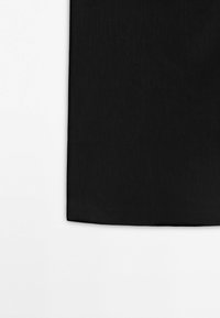 Tissu noir avec une couture cousue courant verticalement le long du bord gauche sur un fond blanc.