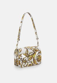 Vit väska med ett blommigt mönster i gult och grönt, rektangulär form, justerbar rem och detaljer i silverfärg.