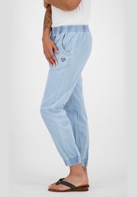 Jasnoniebieskie, lekkie bawełniane spodnie dresowe z elastycznym pasem, bocznymi kieszeniami i drobnym haftem w kształcie brązowego serca.