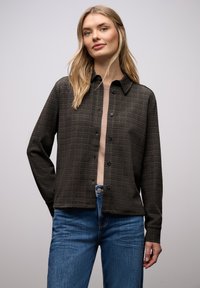 Camicia a quadri scura con bottoni, realizzata in tessuto morbido con colletto, maniche lunghe e vestibilità comoda, abbinata a jeans blu.