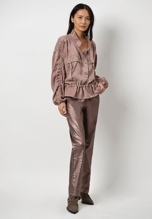 Licht mauve satijnen top met een peplum zoom en ingezette mouwen, gecombineerd met glanzende mauve broeken. Schoeisel zijn bruine enkelboots.