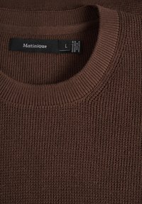 Pull marron en maille à col rond avec une étiquette noire indiquant "Matinique" et la taille "L", cousue à l'intérieur du col.