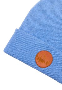 Jasnoniebieska dziana czapka z brązową skórzaną łatą z motywem niedźwiedzia i lasu, prezentująca miękką fakturę i dopasowany kształt.