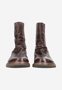 Bottes de cheville en cuir marron avec un haut souple, bout rond et semelles en caoutchouc, présentant une finition mate et un matériau texturé.