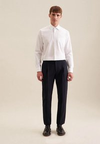 Witte cropped overhemd met knopen en lange mouwen, gecombineerd met donkerblauwe op maat gemaakte broek en zwarte schoenen. Gladde stof, minimalistisch design.