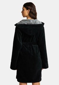 Zwarte kaproen met een zachte textuur, voorzien van een grijze binnenvoering. Inclusief een strikceintuur en lange mouwen met een comfortabele pasvorm.