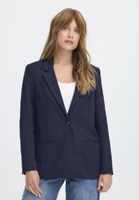 Mornarska blazer jakna od glatkog materijala, s jednim dugmetom, reznim reverima i dva prednja džepa. Jednostavan, strukturiran dizajn.