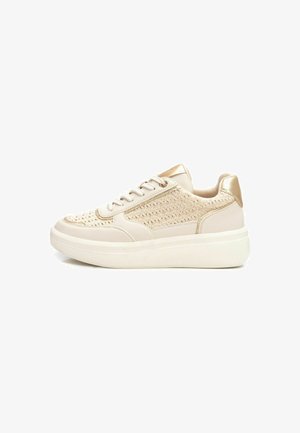 Sneaker beige con una texture superiore intrecciata, dettagli dorati, punta rotonda e una suola bianca spessa per un'altezza aggiuntiva.