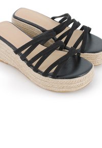 Sandalias negras de cuña con tiras de ante entrelazadas, una zona de los dedos de cuero suave y una suela de plataforma de yute natural texturizado.