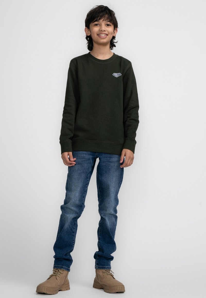 Donkergroene sweatshirt met een ronde hals, blauwe denim jeans en bruinachtige laarzen met veters en een stevige zool. Casual, eenvoudig ontwerp.