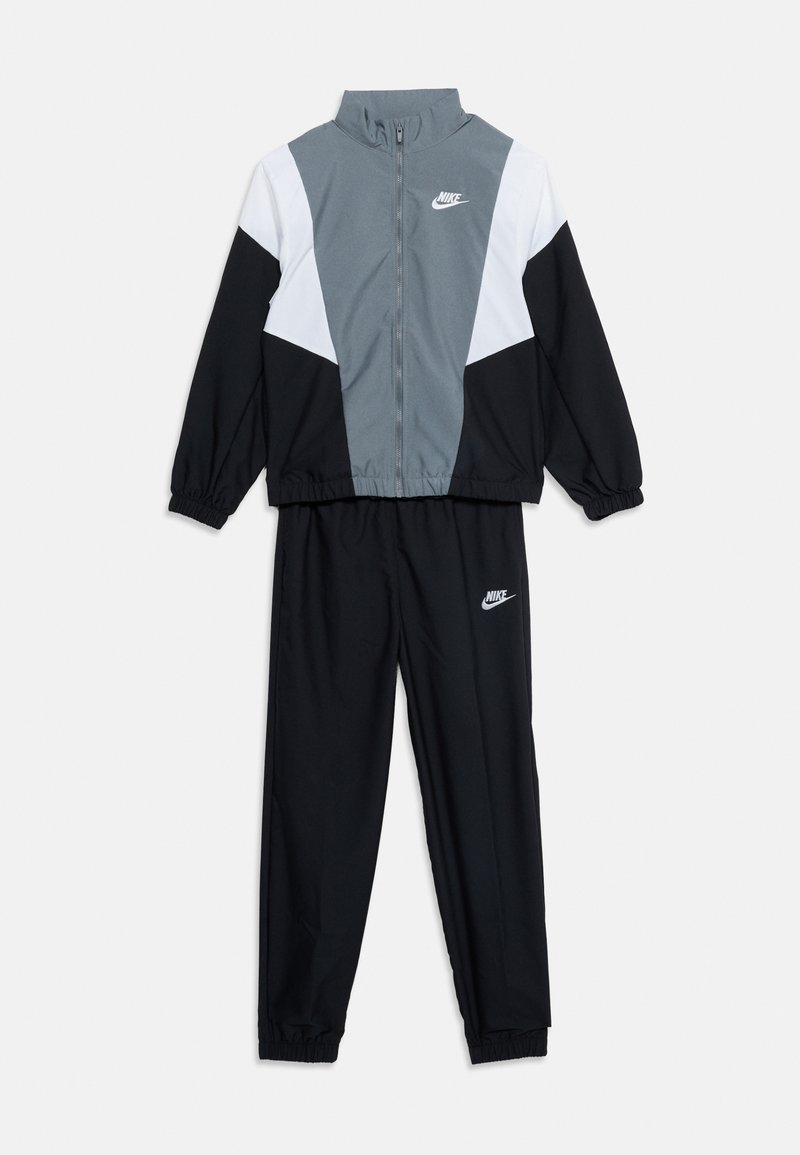 Dvojdielna súprava Nike so sivými, bielymi a čiernymi farebnými blokmi, s bundou na zips a elastickými manžetami, logami Nike na bunde a nohaviciach.