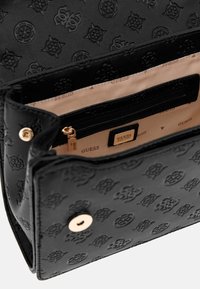 Borsa a tracolla in pelle sintetica nera con motivo logo in rilievo, hardware dorato e interno in tessuto con tasca con zip.