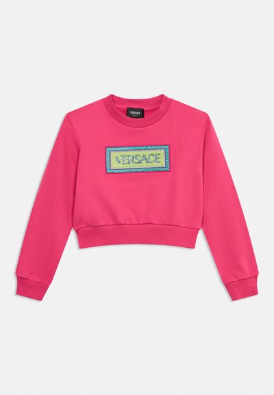 Φουξια cropped φούτερ με μακριά μανίκια και ορθογώνιο έμπλαστρο που απεικονίζει τη λέξη "VERSACE" με μπλε και πράσινη ραφή.