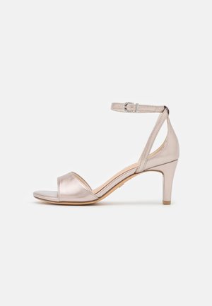Women's metallic beige open-toe sandal with low heel and ankle strap featuring a silver buckle, displayed on white background.