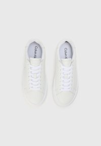 Valged nahast tennisekotid valgete paeltega, lame tallaga ja lihtsa disainiga. Omavad logo keeles ja sujuvat tekstuuri.