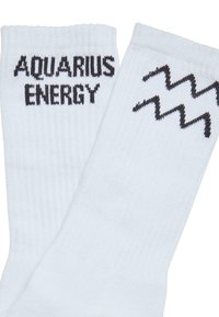 Hvide bomuldsstrømper med ribbet tekstur, hvor "AQUARIUS" og "ENERGY" er broderet med sort tekst, samt et sort zigzag mønster.