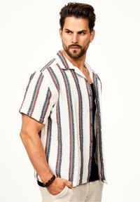 Kurzarmpf Shirt in Weiß mit roten und navyblauen vertikalen Streifen, mit Kragen und strukturiertem Stoff. Mit Knöpfen akzentuiert.