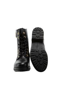 Schwarze Leder-Ankle-Boots mit goldenen Ösen und schwarzen Schnürsenkeln. Dicke, strukturierte Gummisohle mit Sternmustern. Seitlicher Reißverschluss für einen einfachen Zugang.