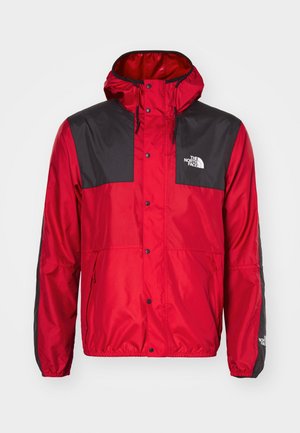 Giacca a vento rossa e nera con cappuccio; presenta bottoni a pressione, tasche laterali e il logo "The North Face" sul petto sinistro.