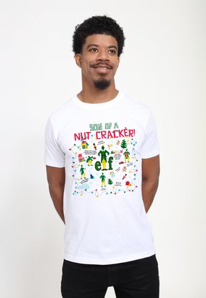 Weißes Baumwoll-T-Shirt mit bunten Grafiken und dem Text „SON OF A NUT CRACKER!“ sowie Illustrationen von Elfen, Geschenken und Weihnachtselementen.