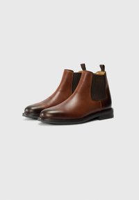 Brown leather Chelsea boots with elastic side panels, round toes, and a low stacked heel. Smooth texture with contrast stitching detail.