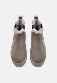 Een paar grijze suede slippers met een zachte fleece voering en trek lussen, van bovenaf bekeken op een witte achtergrond.