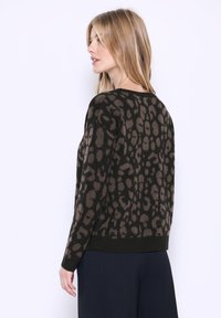 Maglione lavorato a maglia con una stampa leopardata marrone e nera, dotato di scollo rotondo e maniche lunghe. L'orlo è aderente e testurizzato.